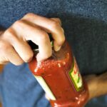 Man using a dish towel to get a better grip on a jar lid