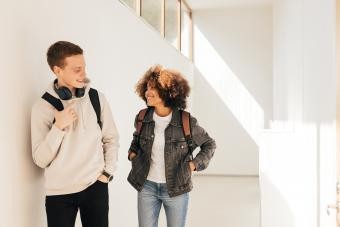 Young man and young woman in hallway talking and smiling