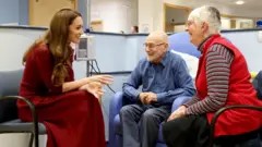 PA Media The Princess of Wales speaks to an elderly man and woman who are smiling as they talk with the princess inside the Royal Marsden Hospital