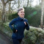 Woman running on a country road in cold weather, representing aerobic exercise to improve VO2 max.