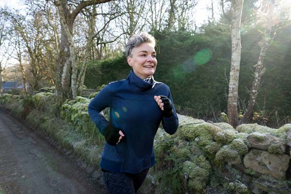 Woman running on a country road in cold weather, representing aerobic exercise to improve VO2 max.