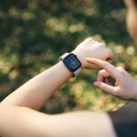 Woman checking heart rate on smartwatch, wrist level