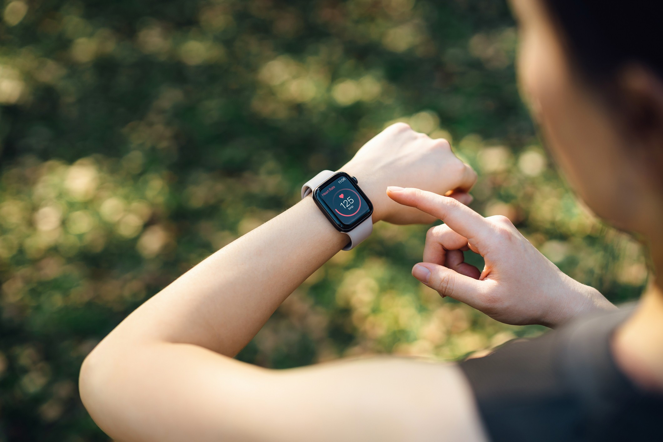 Woman checking heart rate on smartwatch, wrist level