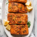 Close-up of air fryer salmon garnished with lemon wedges and parsley, showcasing its perfectly cooked and flaky texture