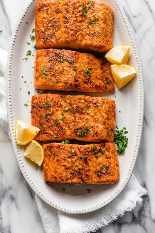 Close-up of air fryer salmon garnished with lemon wedges and parsley, showcasing its perfectly cooked and flaky texture