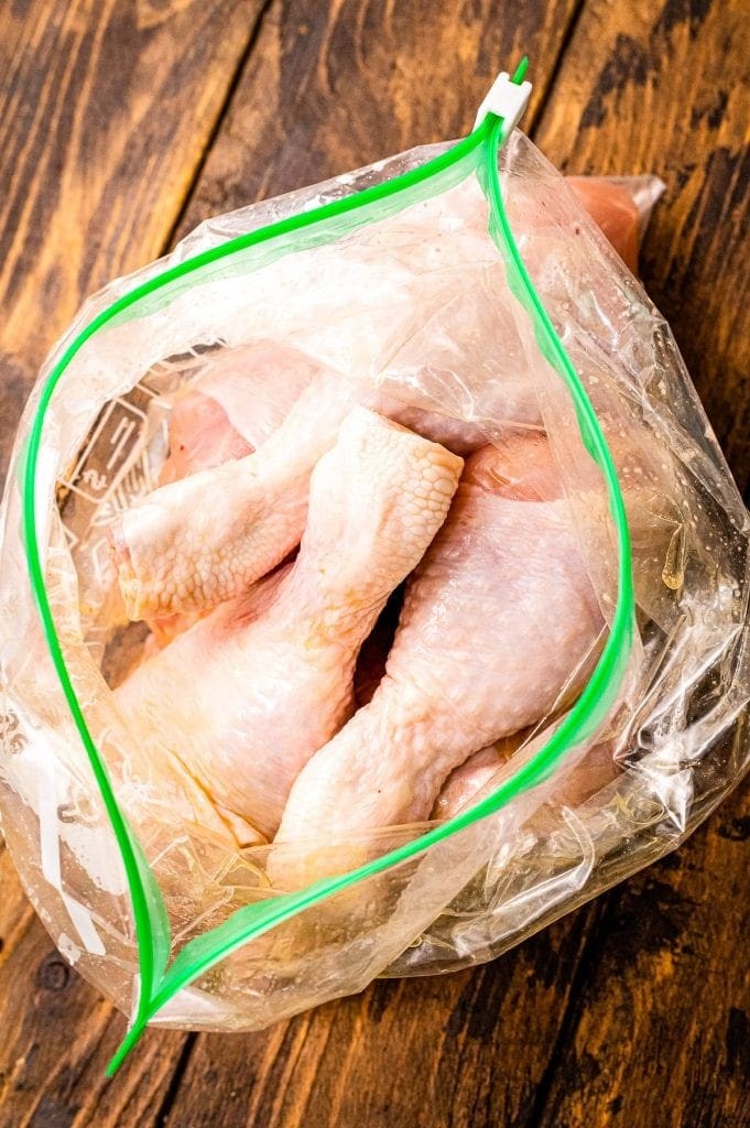 Raw chicken drumsticks in a resealable bag with olive oil, preparing for seasoning.