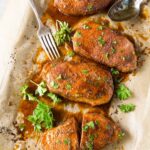 baked pork chops on baking sheet with parsley garnish