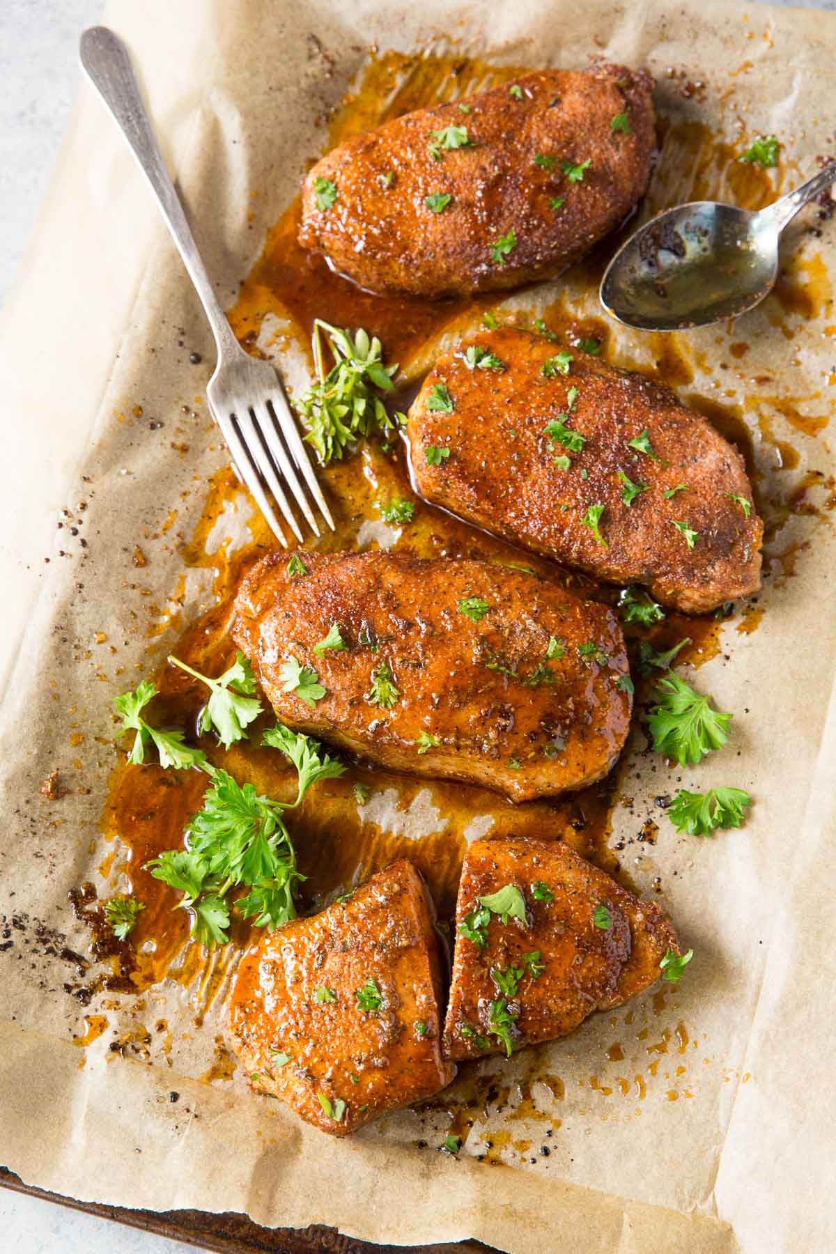 baked pork chops on baking sheet with parsley garnish