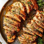 Close-up of juicy baked pork tenderloin slices on a cutting board, ready to serve.