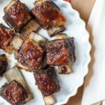 Braised & Seared Beef Bone In Short Ribs with BBQ Sauce In A Yellow Shallow Round Baking Dish