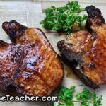 Raw thick-cut bone-in pork chops seasoned with a dry rub, ready for the air fryer.