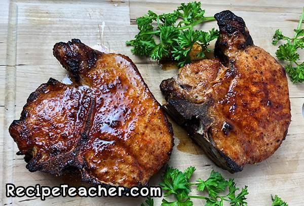 Raw thick-cut bone-in pork chops seasoned with a dry rub, ready for the air fryer.