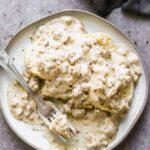 Biscuits and gravy on a plate with a bite taken out by a fork.