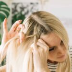 Woman preparing to dutch braid her hair, parting hair with hair extension clipped in, demonstrating initial setup for braid with extensions