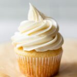 A close-up of a perfectly piped buttercream frosting swirl on a cupcake, showcasing its smooth texture and defined edges.