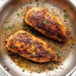 Two seasoned chicken breasts ready to be cooked in a skillet