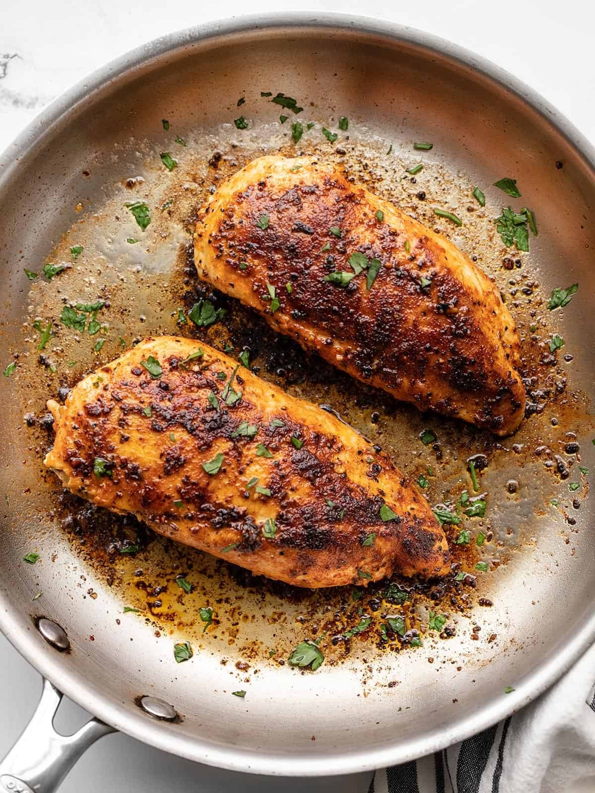 Two seasoned chicken breasts ready to be cooked in a skillet