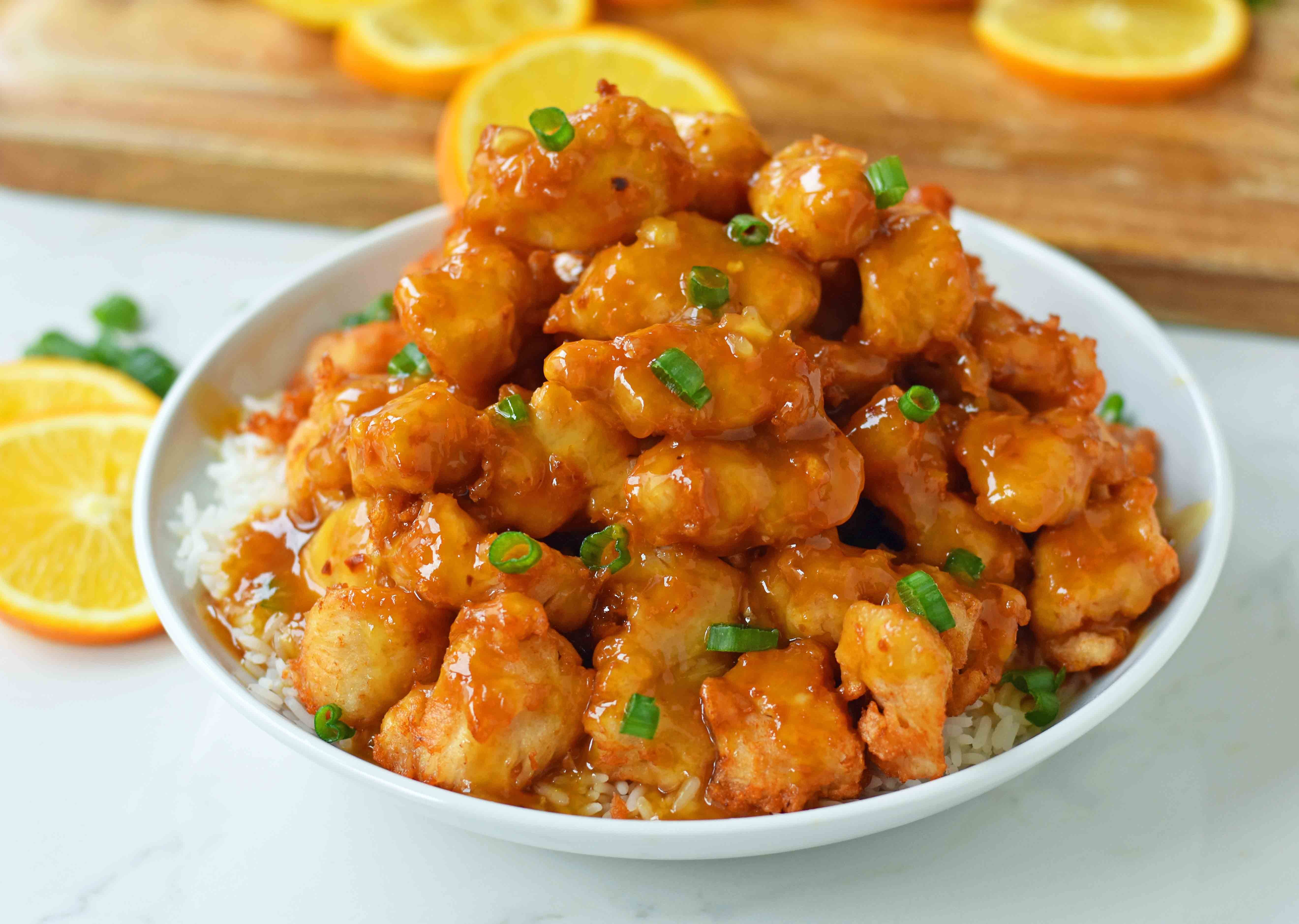 Close-up of homemade Orange Chicken featuring crispy chicken and a vibrant orange sauce, garnished with orange zest and green onions.