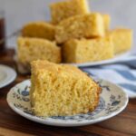 Slice of cornbread on a plate, showcasing its moist and crumbly texture.