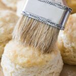 Brushing melted butter on a freshly baked homemade biscuit