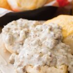 sausage gravy served over open faced biscuits on white plate