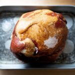 A ham, fat side up, in a roasting pan with a little bit of water.