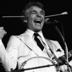 Steve Martin with his banjo while wearing his arrow through the head toy onstage in Chicago