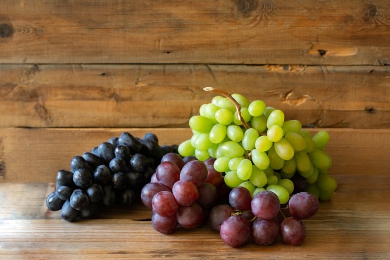 A variety of red, green, and black grapes are displayed, highlighting their identical nutritional value.