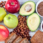 Healthy plant-based foods rich in fiber such as avocados, nuts, seeds, apples, legumes, and whole grains aiding in healthy digestion.