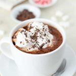 Creamy homemade hot chocolate in mugs, topped with whipped cream and chocolate shavings.