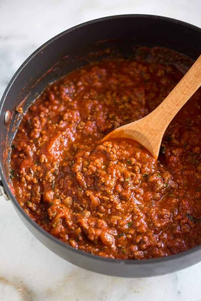 Homemade spaghetti sauce in a saucepan with a wooden spoon