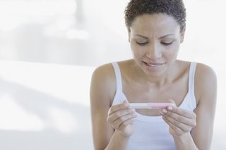 A woman thoughtfully examines a home pregnancy test, contemplating the results.