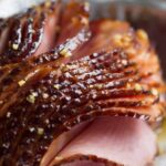 Close-up of a baked ham with a shiny glaze, showcasing its moist and flavorful texture.