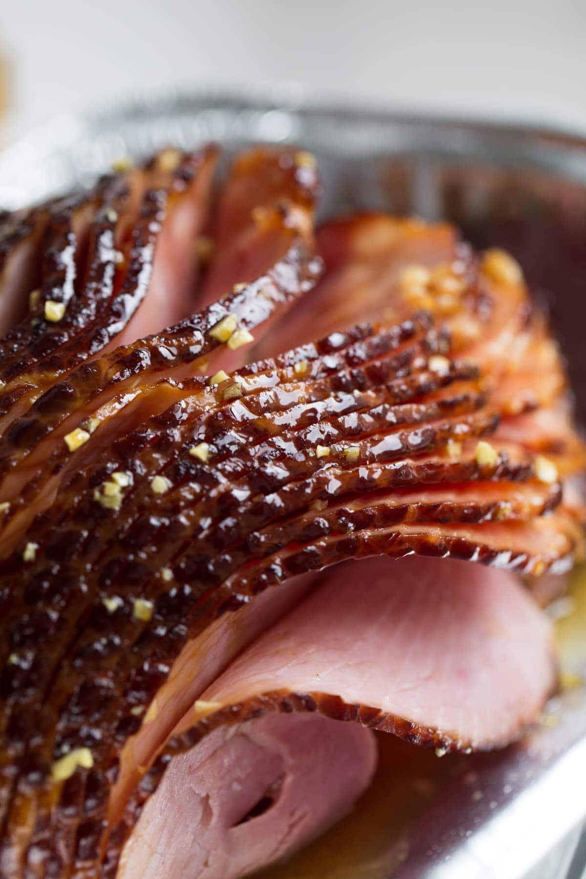 Close-up of a baked ham with a shiny glaze, showcasing its moist and flavorful texture.