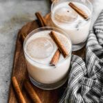 Two glasses of homemade horchata, a refreshing Mexican rice milk drink, garnished with cinnamon sticks.