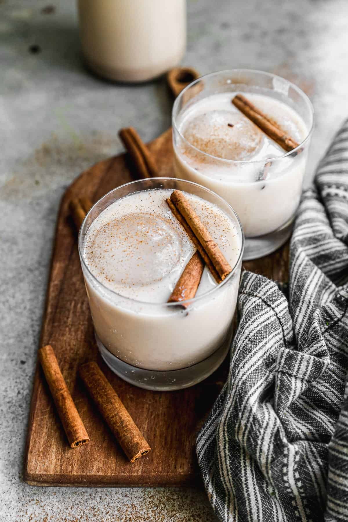 Two glasses of homemade horchata, a refreshing Mexican rice milk drink, garnished with cinnamon sticks.