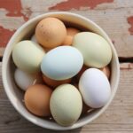 Bowl of fresh eggs with straw and rustic background