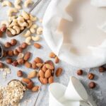 cashews, filberts, almonds, oats and shredded coconut scattered next to a bowl filled with cheese cloth and almond milk for how many tablespoons in 1/3 cup