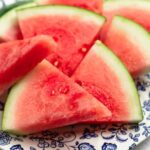 Close up vibrant watermelon wedges on a blue and white plate, showcasing juicy red flesh.