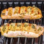 two pieces of salmon on the grill. Flesh side with grill marks up.