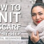 Girl wearing a white knitted scarf, showcasing beginner knitting project