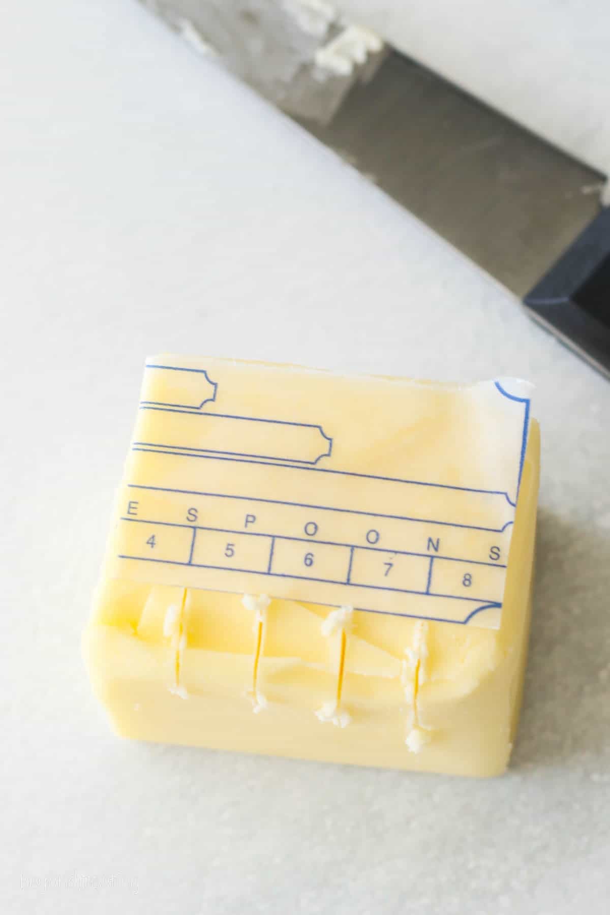 A stick of butter with score marks along the edge of the wrapper, indicating where to cut for precise measurements.