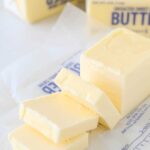 An unwrapped stick of butter sliced into squares, illustrating tablespoon measurements.