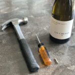 Opening a wine bottle without a corkscrew using a screw, screwdriver, and hammer. Step-by-step guide for a DIY wine opening hack.