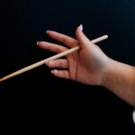 holding chopsticks between thumb and forefinger and resting on ring finger