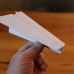 Man holding a paper airplane and smiling, ready to launch it into the air.