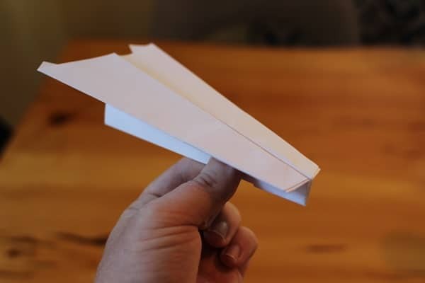 Man holding a paper airplane and smiling, ready to launch it into the air.