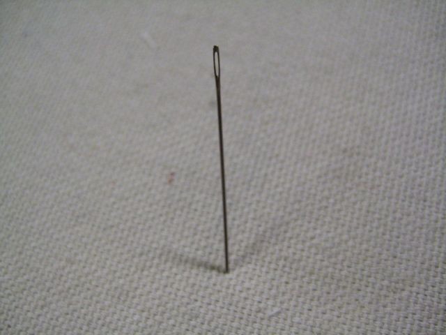 Needle secured in fabric for one-handed threading