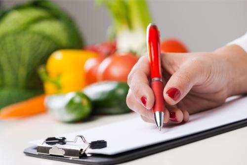 Nutritionist writing food in background, illustrating healthy diet choices for managing creatinine levels