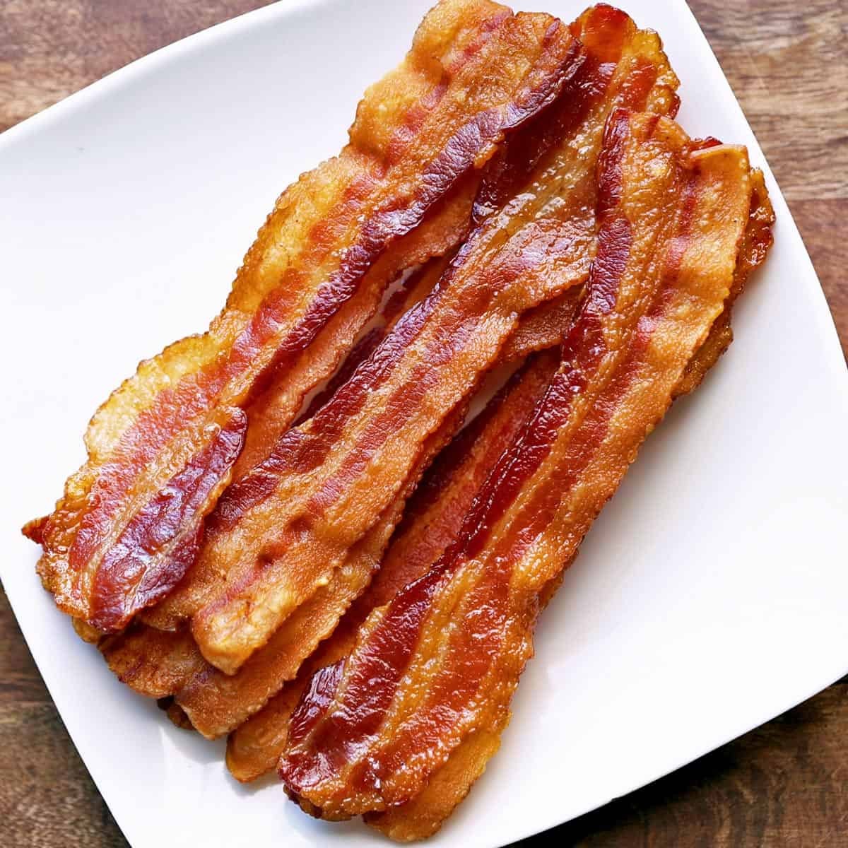 Crispy oven-baked bacon served on a white plate, showcasing its perfect texture and color.